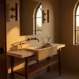 Beige travertine fluted console sink with oak wood stand and integrated backsplash, bathed in warm natural light.