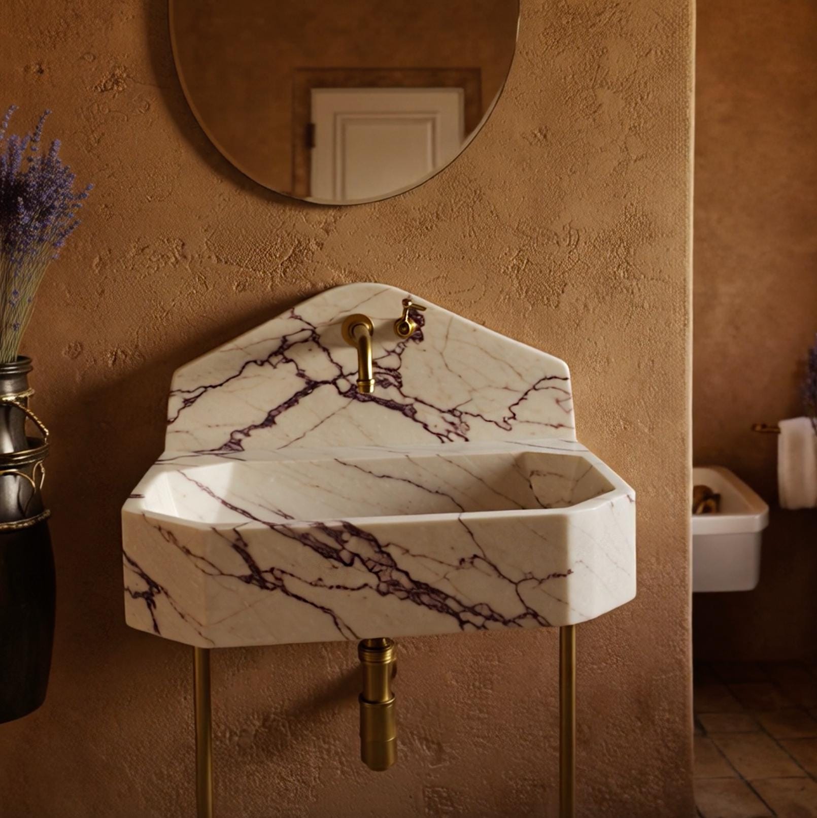 Luxury bathroom console sink featuring brass legs and sculptural Calacatta Viola marble form.