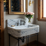 Calacatta Viola fluted marble sink with curved integrated backsplash and matte black metal console stand.