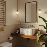 Carrara marble fluted vessel sink with hand-carved details, placed on a floating wood vanity.