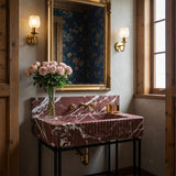 A fluted console sink carved from Imperial Bordeaux marble with a seamless backsplash, designed for elegant, richly toned interiors.