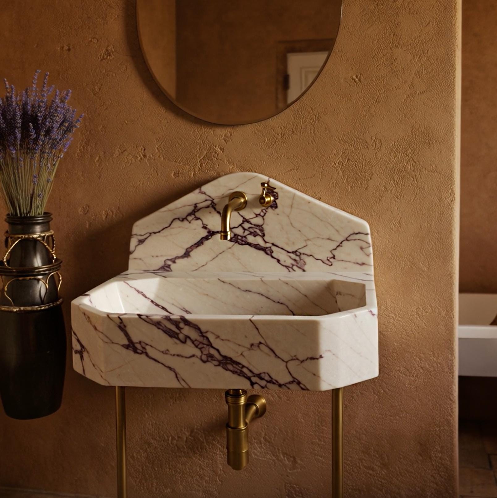 European-inspired console sink in bold Calacatta Viola marble, brass leg frame, and angular form.