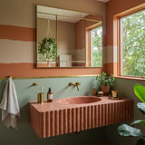 Red travertine fluted floating sink with hand-carved stone design and wall-mounted installation.