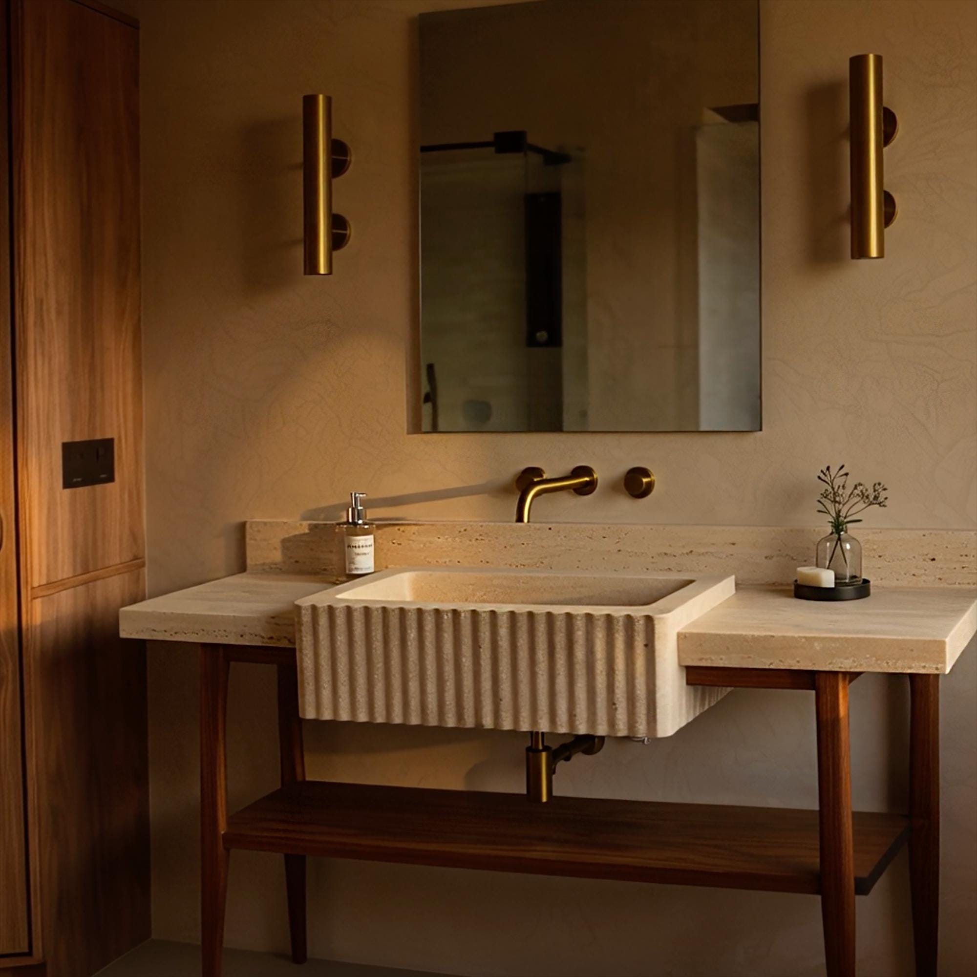 Handcrafted travertine sink with vertical fluting, oak vanity stand, and a timeless stone backsplash for classic interiors.