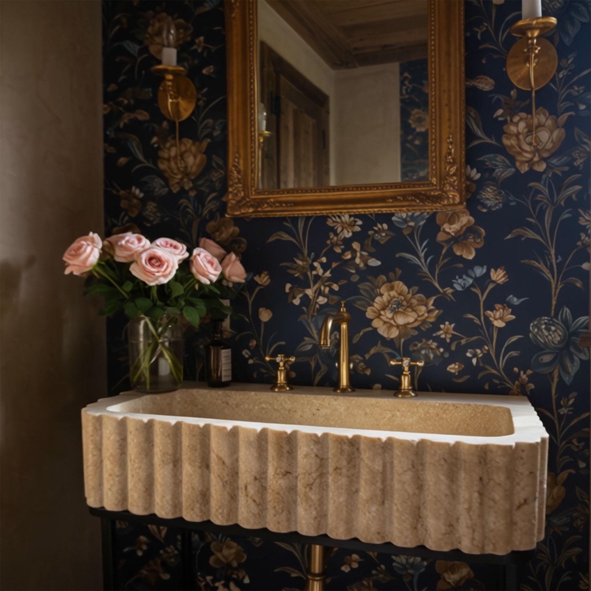 Elegant beige travertine sink featuring fluted texture and minimalist black frame, complemented by floral wallpaper.